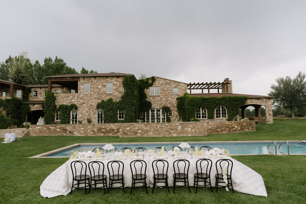 Poolside wedding reception table with black chairs and butter yellow details