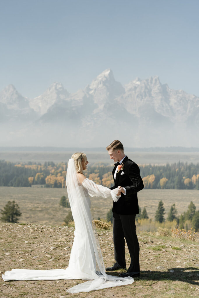 Tetons stand tall in the background of bride and groom in Wyoming