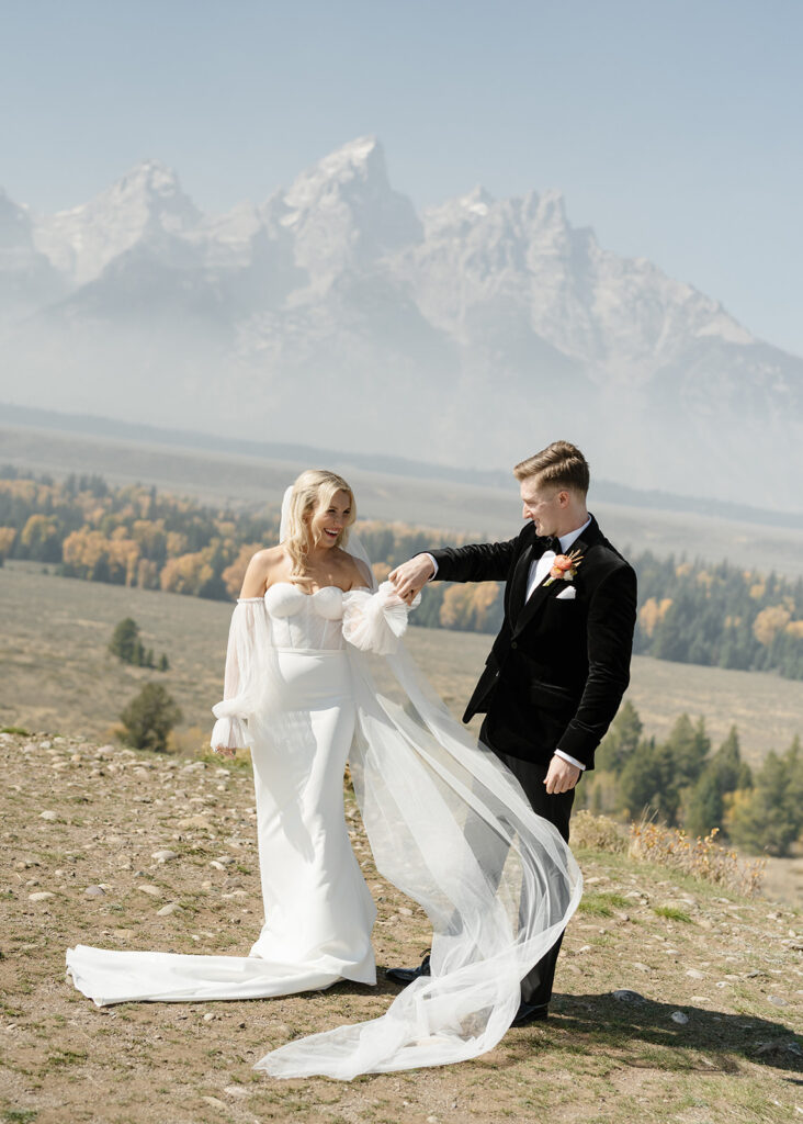 Tetons stand tall in the background of bride and groom in Wyoming