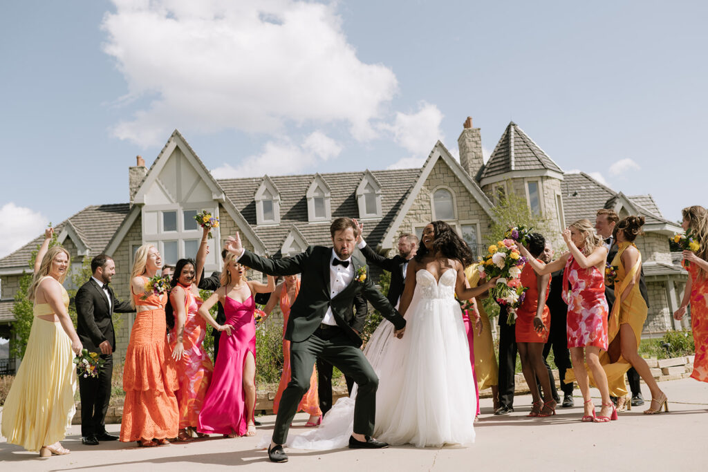 Bride and groom stand in front of Greystone Castle with their wedding party