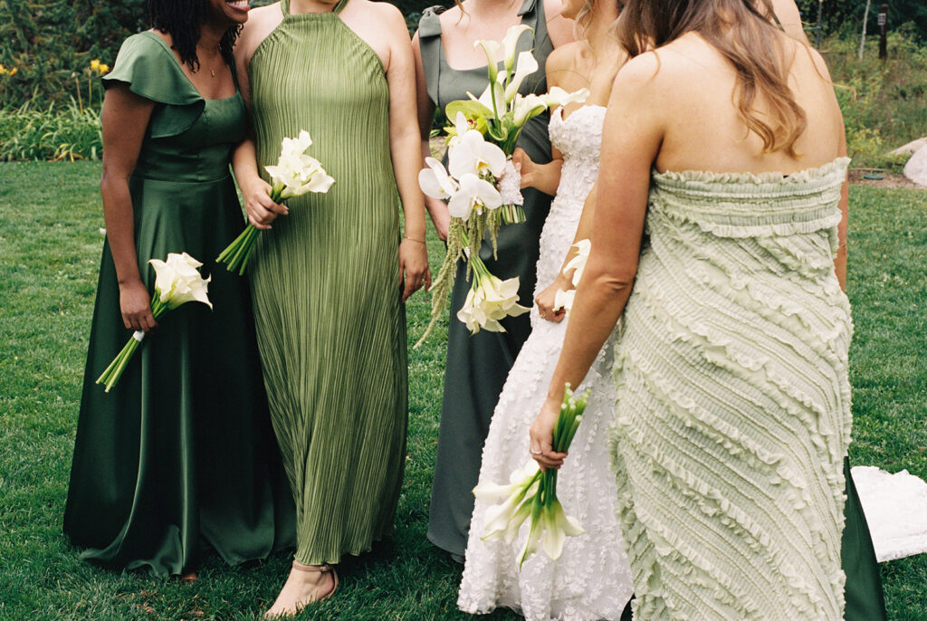 Bride stands with her bridesmaids wearing green bridesmaids dresses