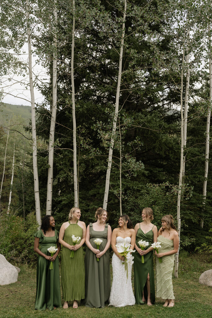 Bride stands with her bridesmaids wearing green bridesmaids dresses