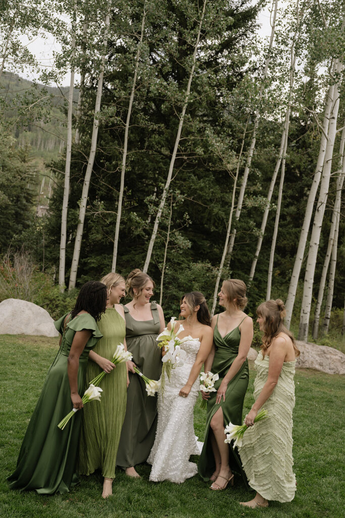 Bride stands with her bridesmaids wearing green bridesmaids dresses