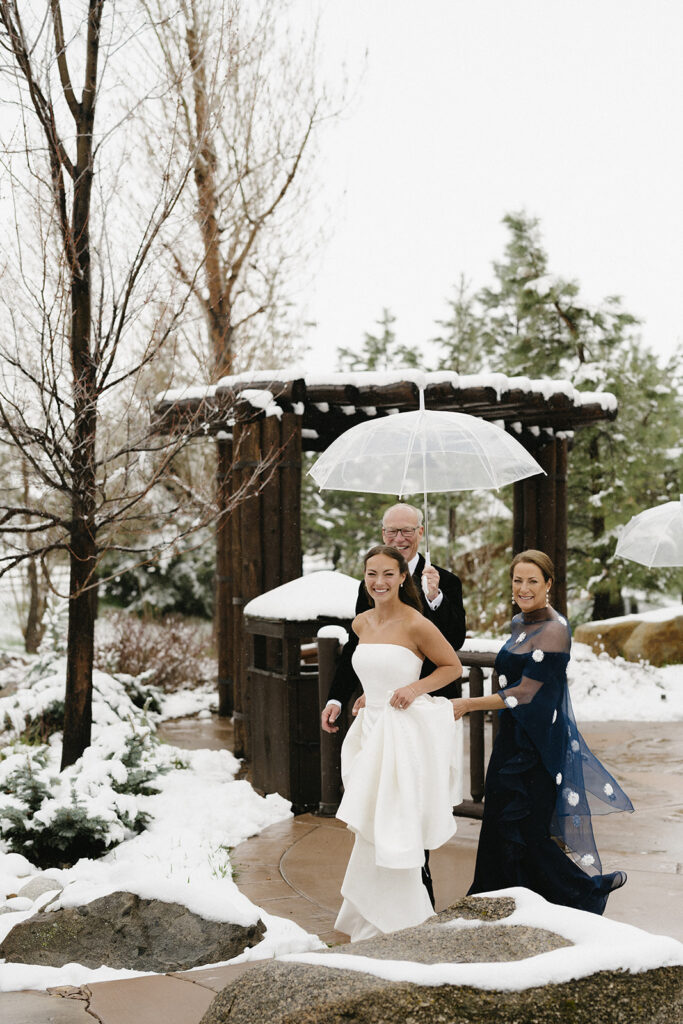 Bride walks with mom and dad to her Colorado winter wedding ceremony