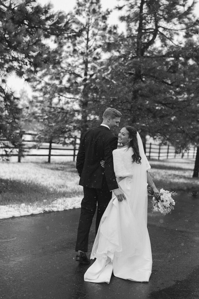 Bride and groom walking hand in hand on snowy road during Colorado winter wedding