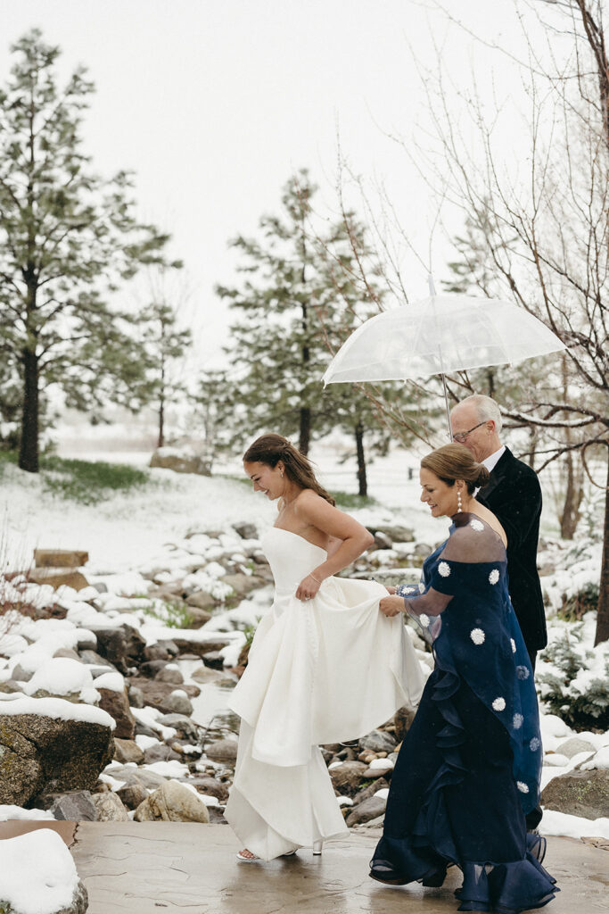 Bride walks with mom and dad to her Colorado winter wedding ceremony