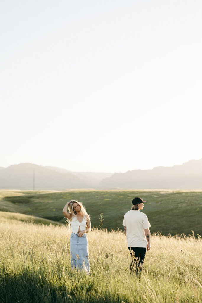 couple walking through field Boulder Colorado golden hour