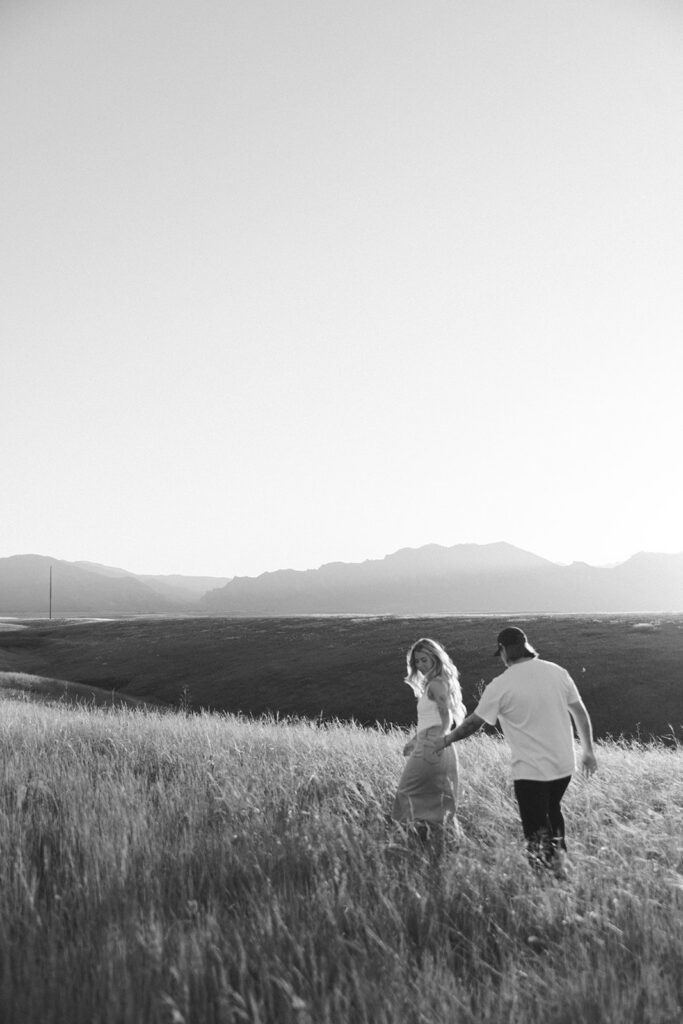 couple walking through field Boulder Colorado golden hour