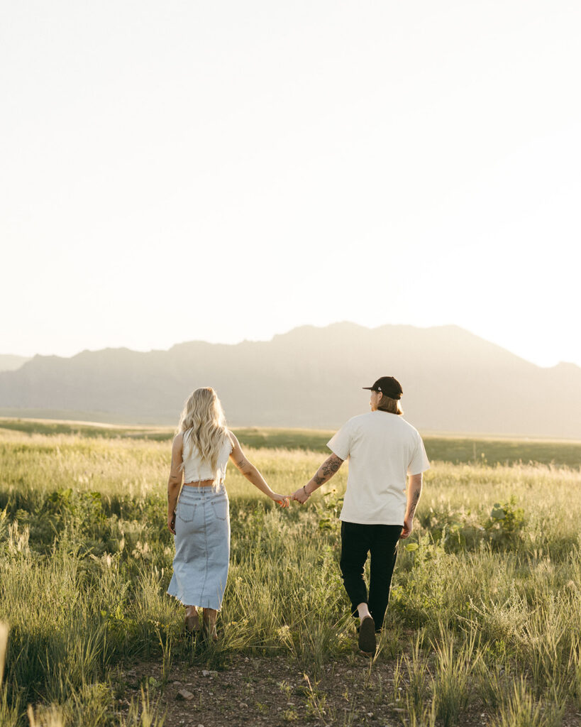 couple walking through field Boulder Colorado golden hour