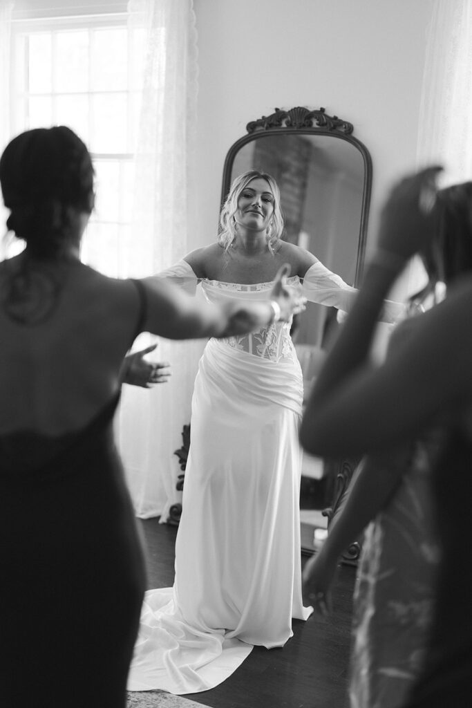 Bride shows her bridesmaids her fully dressed