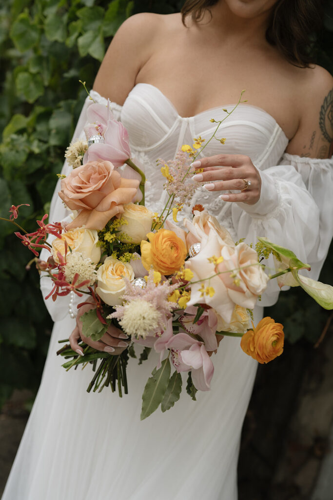 Bride wears a whimsical dress holding a colorful bouquet