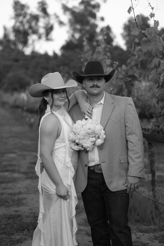 Bride and groom standing in a California vineyard at Rancho Guejito in western wedding attire
