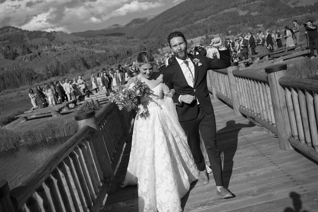 Bride and groom celebrate as they leave their Camp Hale wedding ceremony