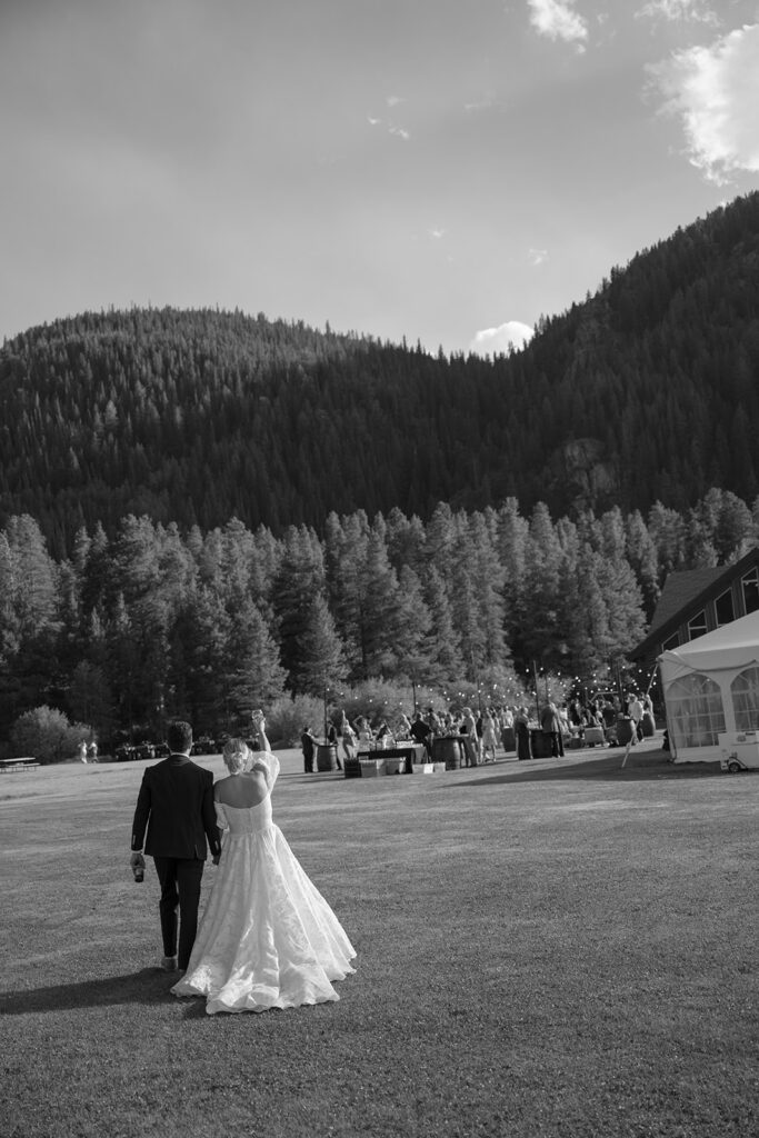 Bride and groom walk to the camp hale reception tent after the ceremony