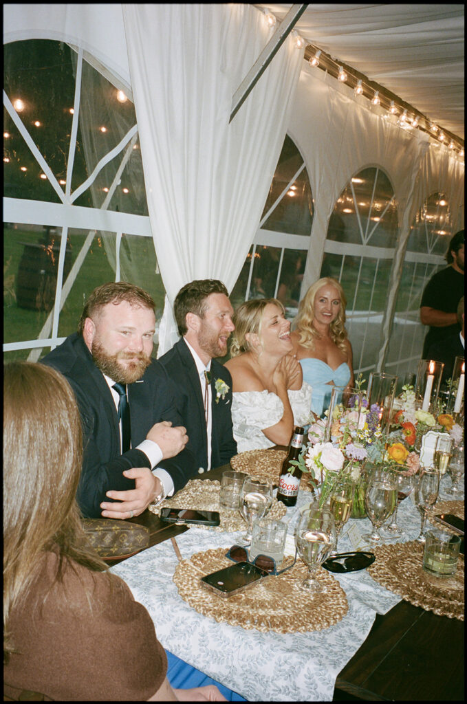 Bride and groom laugh with guests inside the camp hale reception tent