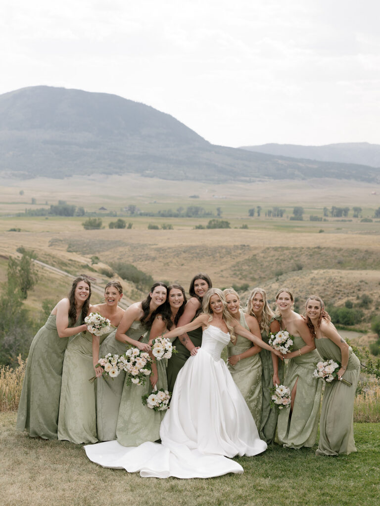 Bride takes a playful group photo with her bridesmaids in their green dresses