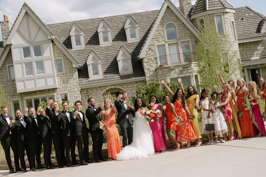 Bride and groom stand with their wedding party in front of a Boulder, Colorado wedding venue: Greystone Castle